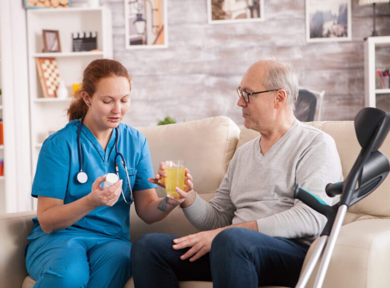 Old man in nursing home helped by female doctor to take his medicine.